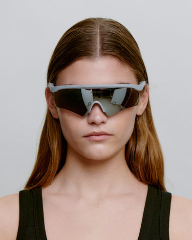 Grå løbe solbriller med mørk glas, set foran på dame