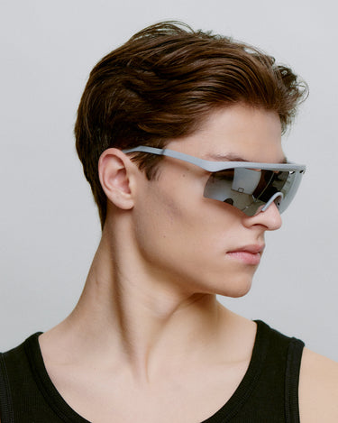 Grå løbe solbriller med mørk glas, set fra siden på herre